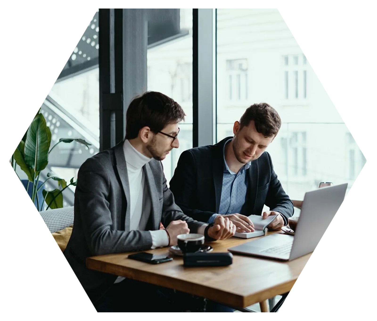 Two businessmen collaborate over documents and a laptop, demonstrating important employability skills.