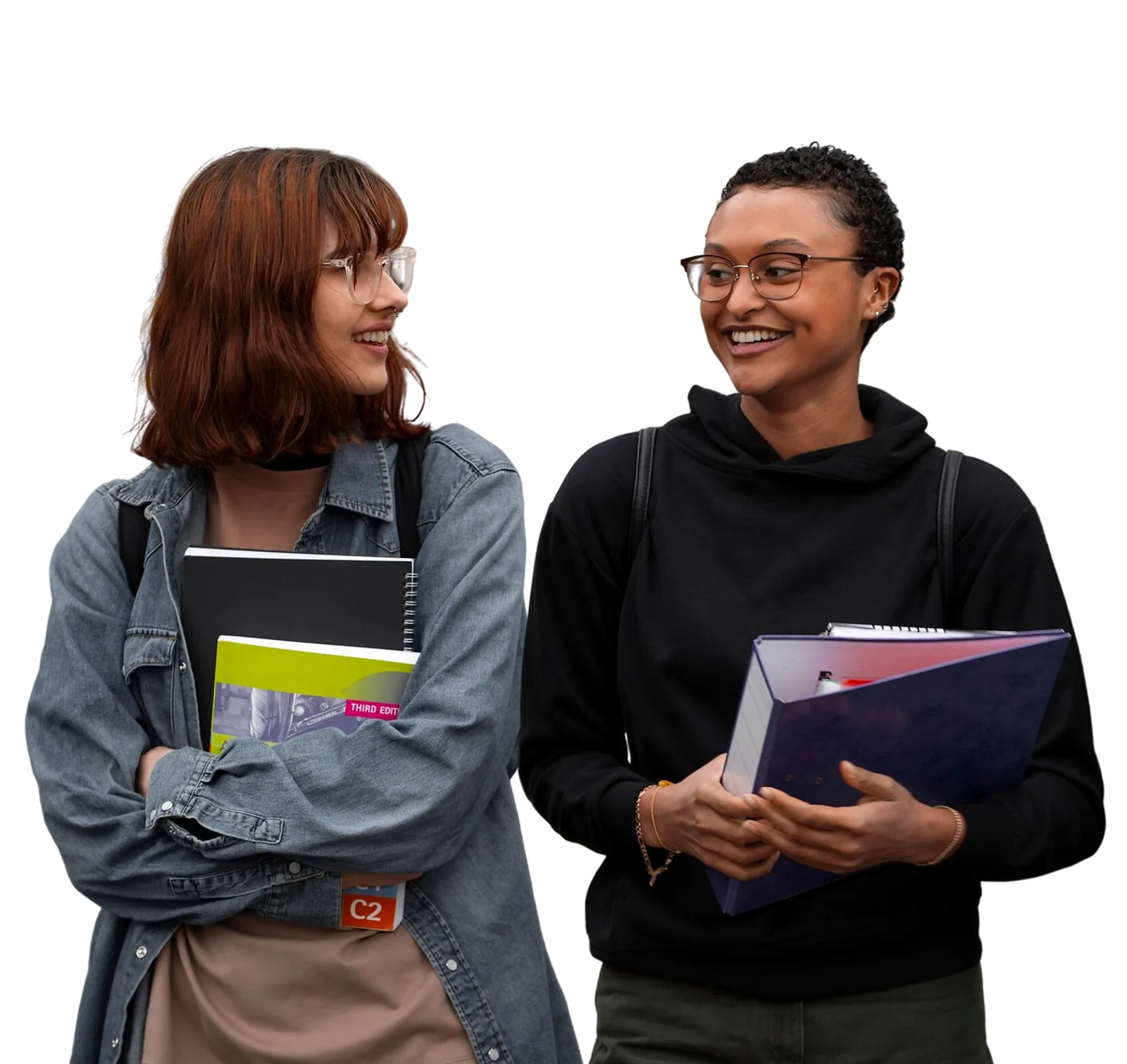 Two students discuss coursework while carrying books and folders during a developing skills program.