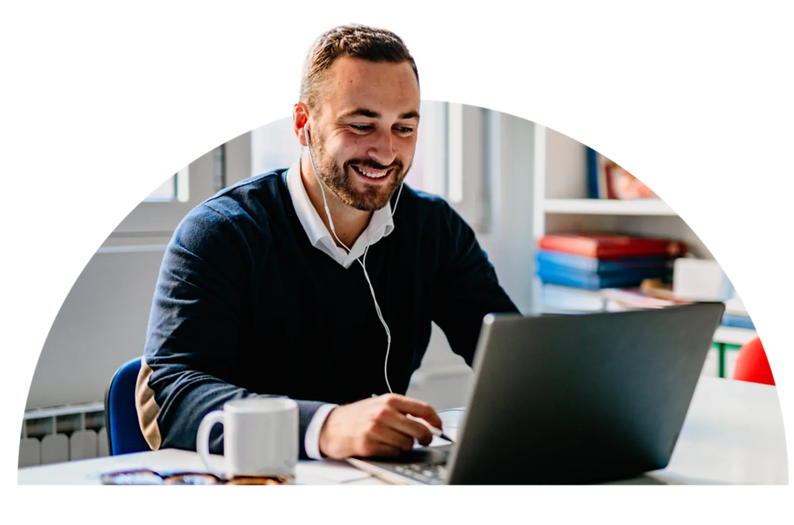 A smiling man works on a laptop while completing LLND training at his desk.